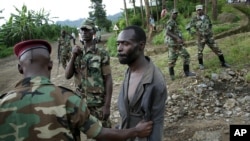 Congolese M23 rebel fighters detain a man suspected to be an FDLR rebel returning from an incursion into Rwanda near Kibumba, north of Goma, November 27, 2012.