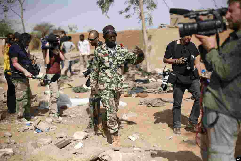 A Malian soldier gestures at journalists to leave the area of a French air strike. Image was taken during an official visit organized by the Malian army to the town of Konna, north of Mali's capital Bamako, January 26, 2013. 
