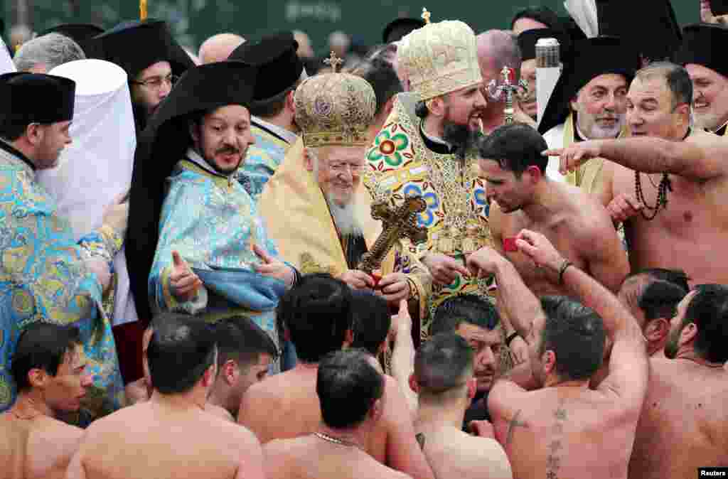 Ecumenical Patriarch Bartholomew I gives presents to Greek Orthodox faithful after they swam into the Golden Horn during the Epiphany day celebrations in Istanbul, Turkey.