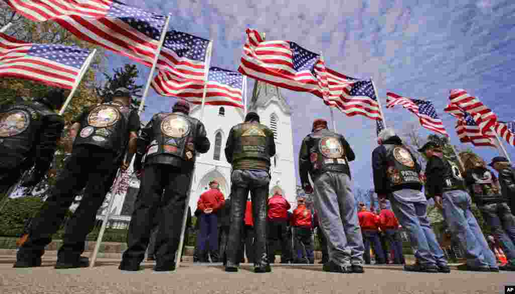 Sebuah klub motor veteran berdiri di luar sambil memegang bendera AS saat berlangsungnya upacara mengenang marinir AS Cpl. Christopher Orlando di gereja Katolik St. Paul di Hingham, Massachusetts. Orlando dan 11 marinir lainnya meninggal 14 Januari lalu dalam misi pelatihan malam hari dengan menggunakan helikopter di lepas pantai Hawaii.