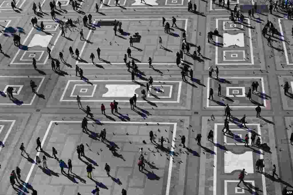 People walk across Duomo square, Milan, Italy.