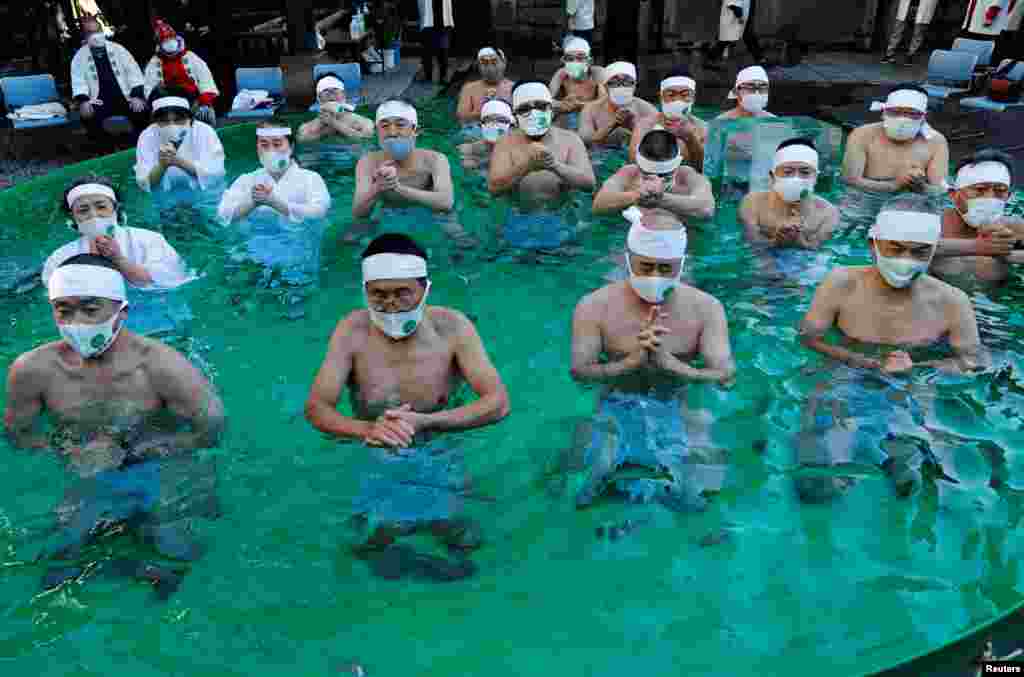 Participants wearing protective face masks amid the COVID-19 outbreak, pray as they take an ice-cold bath during a ceremony to purify their souls and to wish for overcoming the pandemic at the Teppozu Inari shrine in Tokyo, Japan,.