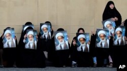 FILE- Anti-government protesters hold posters of top Shiite cleric Sheik Isa Qassim to show their support for him, in Karrana, Bahrain, just outside the capital of Manama, May 17, 2013. Bharain stripped the citizenship of Qassim on June 20, 2016.