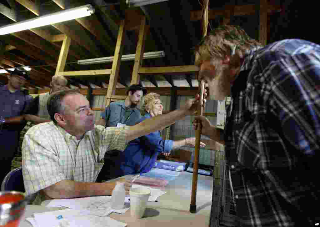Virginia Gov. Timothy M. Kaine, left, examines the walking stick of patient Jerry Austin, of Keokee, as he mans the registration desk during the Remote Area Medical Health Clinic at the fairgrounds in Wise, Virginia, July 24, 2009.
