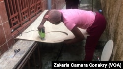 Aicha entrain de scier le bois dans son atelier, à Conakry, Guinée, 13 septembre 2018. (VOA/ Zakaria Camara Conakry)