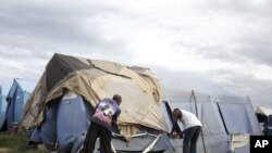 Men try to tie down their tent, which serves as their home, with scraps of material in the slum area of Cite Soleil August 4, 2011.