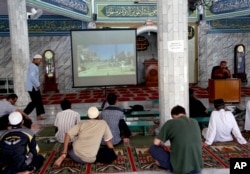 FILE - Muslim men watch a slideshow of pictures believed to be from Syria during a prayer calling for jihad to Syria at a mosque in Jakarta, Indonesia, Dec. 15, 2013.