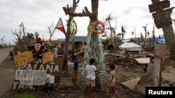 Children, victims of super typhoon Haiyan, decorate their improvised Christmas tree with empty cans and bottles at the ravaged town of Tanuan, Leyte province, central Philippines, Dec. 19, 2013.