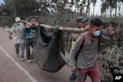 Residents carry a body recovered near the "Volcano of Fire," in Escuintla, Guatemala, June 4, 2018.