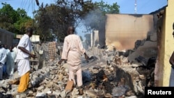 Dua orang berdiri di tengah puing-puing bangunan di wilayah Benisheik, Borno, setelah wilayah itu diserang oleh Militan Boko Haram (19/9/2013).