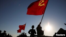 中国解放军军人在内蒙古朱日和训练基地准备参加阅兵，庆祝解放军建军90周年。中共党旗在前，国旗居中，军旗在后（2017年7月30日）