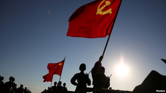 中国解放军军人在内蒙古朱日和训练基地准备参加阅兵，庆祝解放军建军90周年。中共党旗在前，国旗居中，军旗在后（2017年7月30日）