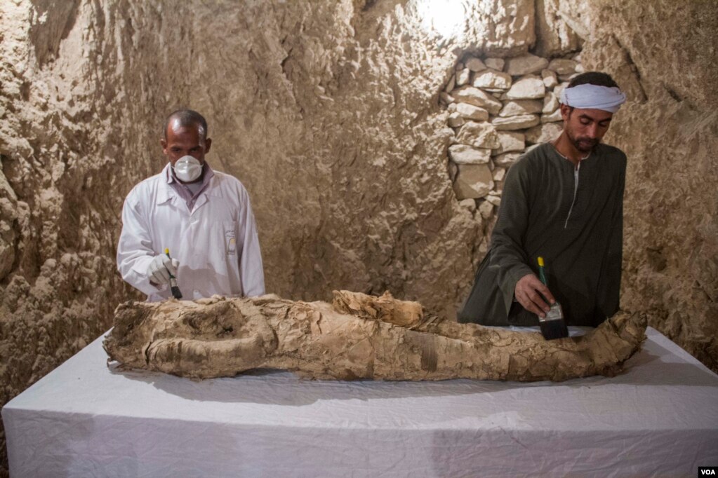 Egyptian excavation workers restore a mummy in a newly discovered tomb, known as Kampp 150, in the Draa Abul Naga necropolis on Luxor’s West Bank, Egypt, Dec. 9, 2017.(H. Elrasam/VOA)