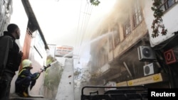 Petugas berusaha memadamkan api akibat tembakan mortir pemberontak di Damaskus, Suriah hari Selasa (15/10). 