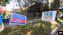 在明尼阿波利斯的一個投票站外，草坪上的一幅標語牌要求選民就取代警察局的公投議題“選票第2問題”投支持票，另一幅呼籲投反對票。 (2021年11月2日)