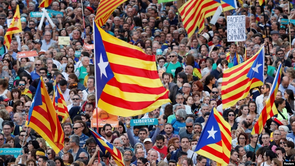Manifestantes agitan banderas separatistas catalanas durante una manifestación organizada por los movimientos independentistas catalanes, tras el encarcelamiento de sus dos líderes Jordi Sánchez y Jordi Cuixart, en Barcelona, el 21 de octubre de 2017.