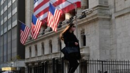 FILE - A person walks past the New York Stock Exchange (NYSE) at Wall Street on November 16, 2020 in New York City.