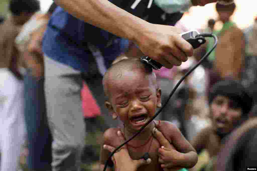 A Rohingya migrant child, who recently arrived in Indonesia by boat, cries as a volunteer cuts his hair inside a temporary compound for refugees in Aceh Timur regency, Indonesia&#39;s Aceh Province.