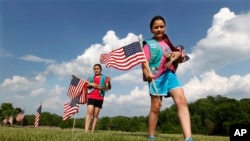 Girl Scouts Sarah and Megan Lontoc, 10, place flags as the scouts placed thousands of flags on veteran's graves at Brig. Gen. William C. Doyle Veterans Memorial Cemetery in honor of Memorial Day, Friday, May 27, 2016, in Wrightstown N.J. (AP Photo)