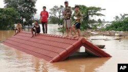 Villagers take refuge on a rooftop above flood waters from a collapsed dam in the Attapeu district of southeastern Laos, July 24, 2018. 