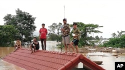 Villagers take refuge on a rooftop above flood waters from a collapsed dam in the Attapeu district of southeastern Laos, July 24, 2018.