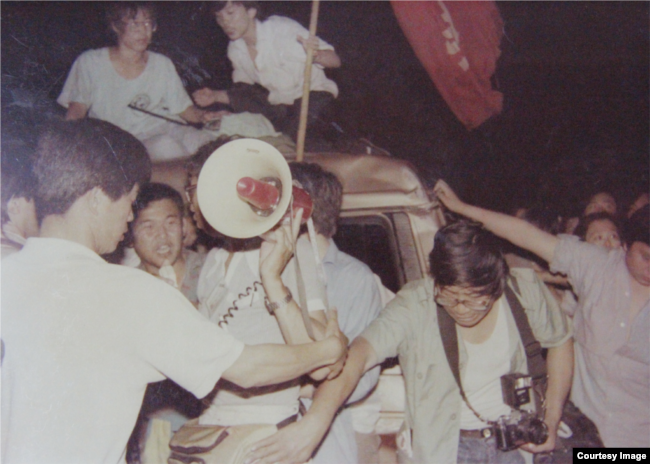 网友寄来照片并写道:“我叫梅实。中间那个拿喇叭的人是我 。 1989年6月2日晚间,一辆军方SUV车撞击4名北京平民,造成3人死亡,我在现场处理,车上有军装军帽。”