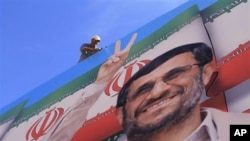 A worker fixes a huge poster of Iranian President Mahmoud Ahmadinejad during preparations for his visit to the southern village of Bint Jbeil, Lebanon, 12 Oct 2010