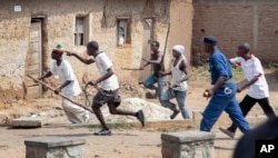 FILE - Members of the Imbonerakure pro-government youth militia chase after opposition protesters, unhindered by police, in the Kinama district of the capital Bujumbura, Burundi, May 25, 2015.