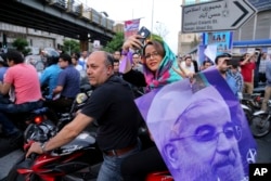 A supporter of Iran's President Hassan Rouhani, who is running for a second term in office, holds his poster during a campaign rally in downtown Tehran, May 16, 2017.