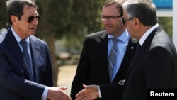 Greek Cypriot leader and Cyprus President Nicos Anastasiades (L) shake hands with Turkish Cypriot leader Mustafa Akinci (R), as UN envoy Espen Barth Eide looks on, in the buffer zone of Nicosia airport, Cyprus, Sept. 14, 2016.