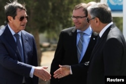 FILE - Greek Cypriot leader and Cyprus President Nicos Anastasiades (L) shake hands with Turkish Cypriot leader Mustafa Akinci (R), as UN envoy Espen Barth Eide looks on, in the buffer zone of Nicosia airport, Cyprus, Sept. 14, 2016.