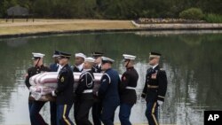 El ataúd del expresidente de EE.UU., George H.W. Bush, cubierto con la bandera, es llevado por una guardia de honor de servicios militares para su entierro en la Biblioteca Presidencial y Museo que lleva su nombre, en College Station, Texas. Dic. 6 de 2018.