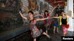 Chinese tourists pose for a picture inside the Grand Palace in Bangkok, May 24, 2014.