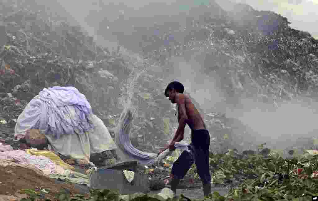 A Bangladeshi dhobi, or laundryman, washes clothes near a garbage dump on the banks of the Buriganga River in Dhaka.