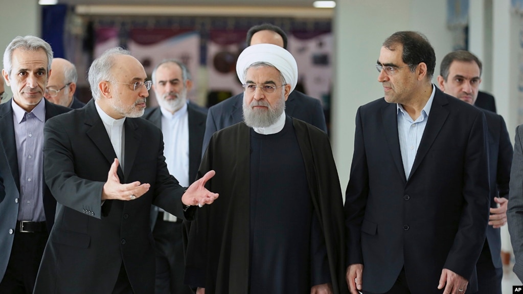 FILE - President Hassan Rouhani (center) listens to head of Iran's Atomic Energy Organization Ali Akbar Salehi (left) while attending a ceremony marking the national day of nuclear technology in Tehran, Iran, Thursday, April 7, 2016. Iran's Health Minister Hassan Ghazizadeh Hashemi is at right.