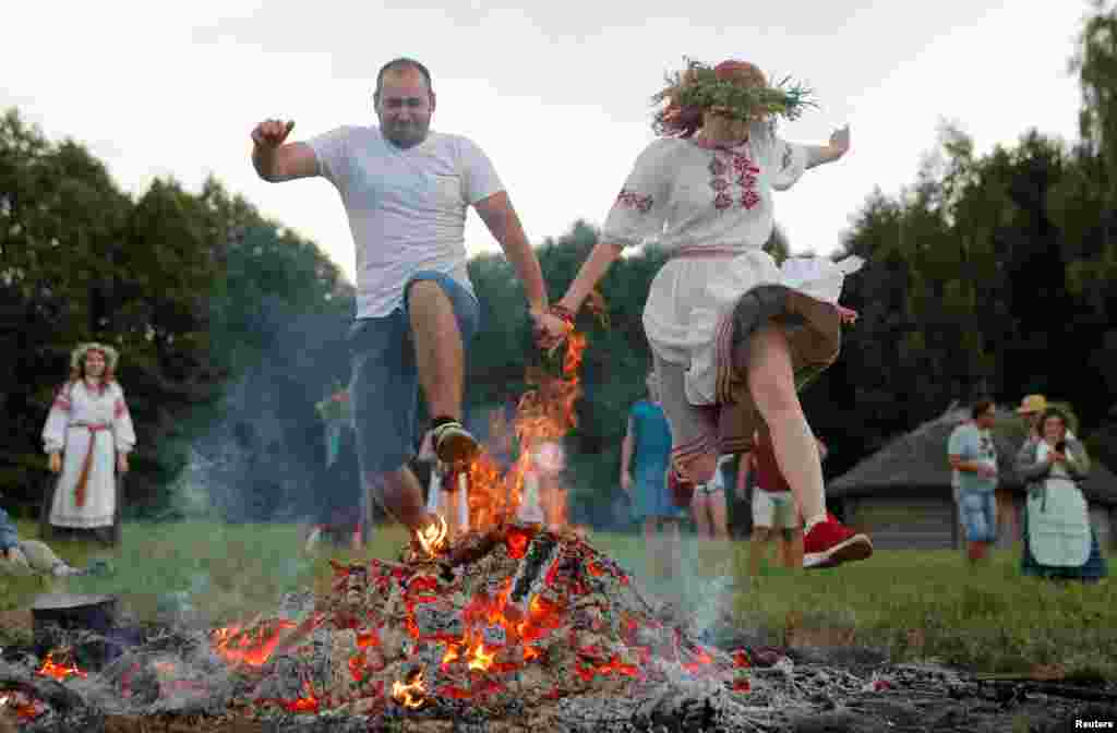 People jump over a campfire as they take part in the Ivan Kupala festival in Belarusian state museum of folk architecture and rural lifestyle near the village Aziarco, July 4, 2020.