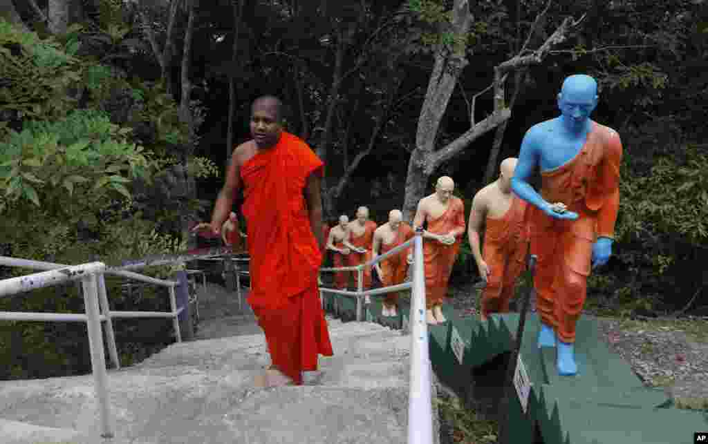 A Sri Lankan Buddhist monk climbs the steps past statues at a deserted temple during curfew on Buddha Jayanthi, a day that celebrates the birth of the Buddha, in Colombo, Sri Lanka, Thursday, May 7, 2020. 