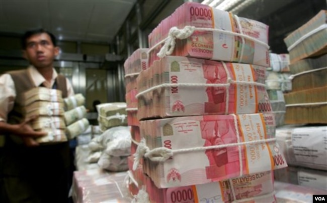 Seorang pekerja di Bank Indonesia mengatur tumpukan mata uang Rupiah (foto: dok).