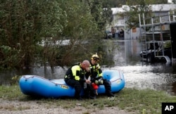 Members of a combined New Bern/Greenville swift water rescue team Brad Johnson, left, and Steve Williams rest after searching for people stranded by floodwaters caused by the tropical storm Florence in New Bern, N.C., Sept. 15, 2018.