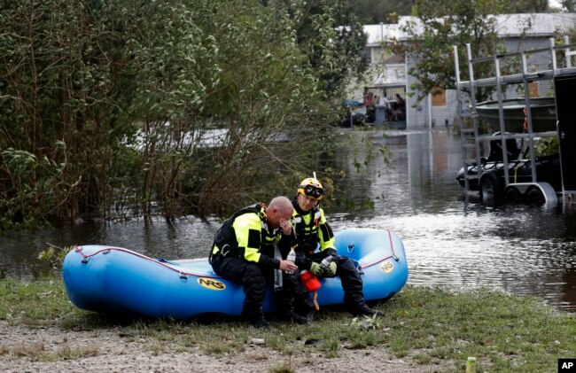 Members of a combined New Bern/Greenville swift water rescue team Brad Johnson, left, and Steve Williams rest after searching for people stranded by floodwaters caused by the tropical storm Florence in New Bern, N.C., Sept. 15, 2018.