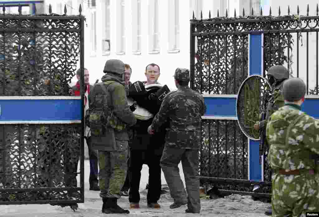 Một sĩ quan hải quân Ukraina mang đồ đạc ra khỏi trụ sở&nbsp;hải quân với binh sĩ Nga tại Sevastopol, ngày 19/3/2014.