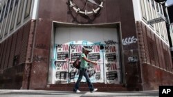 FILE - A woman walks in front of a closed bank in the neighborhood of Rio Piedras in San Juan, Puerto Rico, June 29, 2015. 