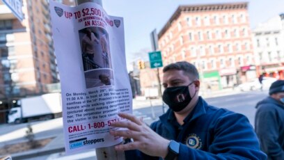 Một cảnh sát viên dán thông báo treo tiền thưởng cho thông tin về người tấn công một người phụ nữ gốc Á gần hiện trường, ngày 30 tháng 3, 2021, ở Thành phố New York.