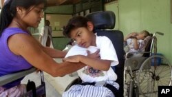 Marielos Sandi, left, helps care for Mora Chavaria, right, at the National Rehabilitation Center in Santa Ana, Costa Rica.