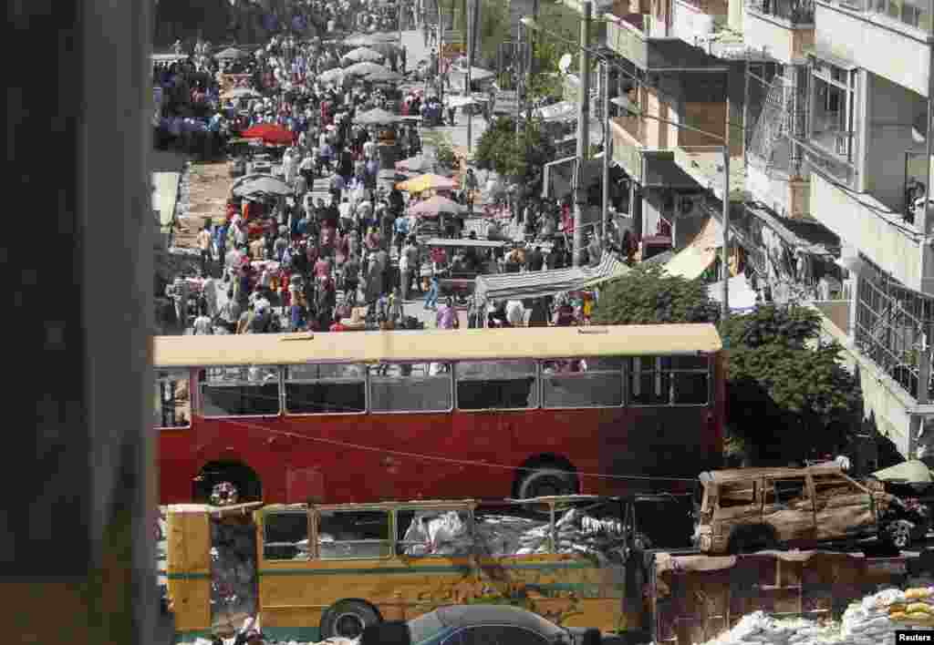 People walk and on the first day of Ramadan in a passageway separating Aleppo's Bustan al-Qasr, which is under the rebels' control, and Al-Masharqa neighborhood, an area controlled by the regime, July 10, 2013. 