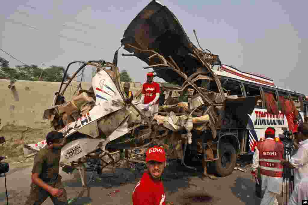 Rescue workers check the wreckage of a bus carrying government employees that was destroyed in a bomb blast, Peshawar, Pakistan, Sept. 27, 2013. 