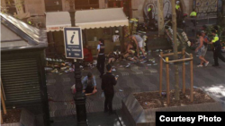 Police officers and bystanders are seen attending to injured people on the ground after a van plowed through a sidewalk, at Las Ramblas, near Placa de Catalunya, in Barcelona, Spain, Aug. 17, 2017. (Courtesy - Jordi Ramos)