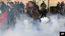 An Egyptian protester throws a tear gas canister fired by security forces during clashes near the Interior Ministry in Cairo, Egypt, Sunday, Feb. 5, 2012.