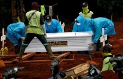Para petugas menggunakan baju pelindung memakamkan korban virus corona (COVID-19) di sebuah pemakaman yang disediakan pemerintah, di Jakarta, 3 April 2020. (Foto: Reuters)