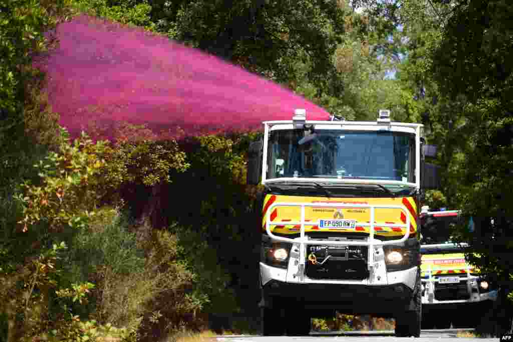 Firefighters spray fire-retardant on trees to avoid flareups of small fires due to wind, during a wildfire in La Garde-Freinel in the department of Var, southern France.